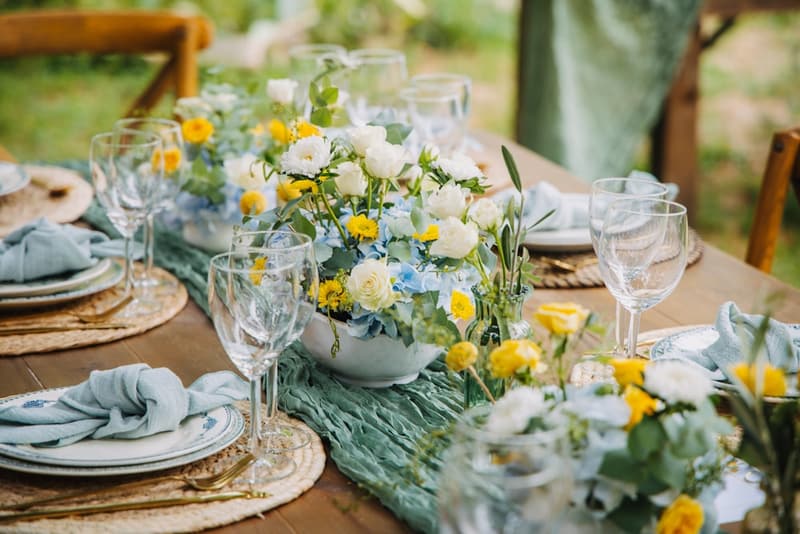 Sage and ivory garden wedding table beside greenery